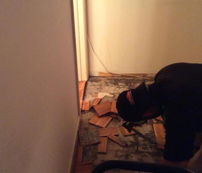 Employee removing dirty wood flooring. 