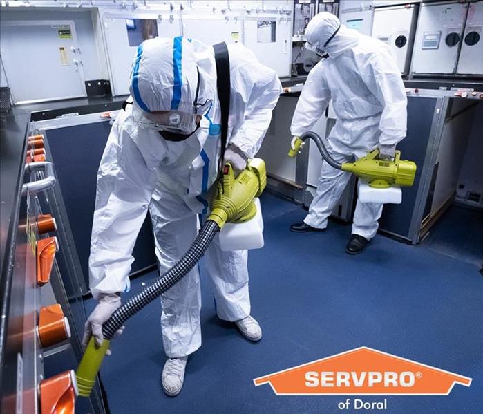 Two people in PPE cleaning.