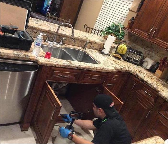 A professional checking water damage in the kitchen of a home.