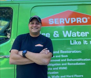 Man smiling in front of servpro van with arms crossed